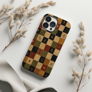 May include: A smartphone case featuring a checkered pattern of muted black, olive green, mustard yellow, and terracotta red squares. Some squares contain small, simple illustrations of flowers, leaves, and star-like shapes in a dark brown color.