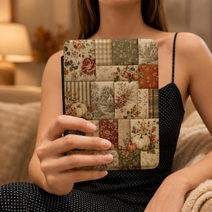 May include: A rectangular e-reader case featuring a patchwork design of various autumn-themed fabric patterns, including floral prints, checkered squares, striped textures, and illustrations of pumpkins, foliage, and rural landscapes in muted earth tones.