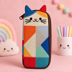 May include: A rectangular pencil case featuring a cat face at the top with one blue ear and one red ear. The body of the case is decorated with a geometric patchwork pattern in shades of orange, yellow, gray, teal, blue, and red, with a brown zipper.