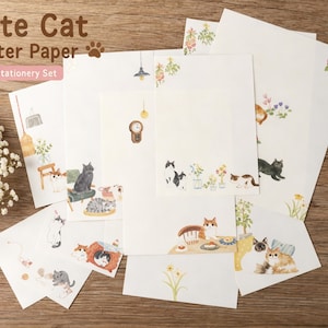 May include: A stationery set with cat illustrations on letter paper and envelopes. The set includes a pen with a cat-shaped top. The paper features various cat-themed designs, including cats in domestic settings, flowers, and the text "Cute Cat Letter Paper".