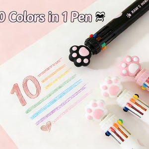 May include: A multi-colored pen with a paw-shaped design. The pen has 10 different colors and the text "10 Colors in 1 Pen". The pen is black, white, and pink. The image also shows a drawing of the number 10 in red and a heart.