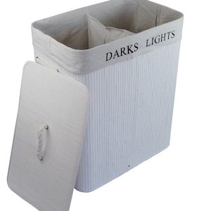 May include: A white laundry hamper with a lid, featuring vertical lines and the text "DARKS LIGHTS" on the rim. The hamper is divided into two sections and has a rope handle on the lid.