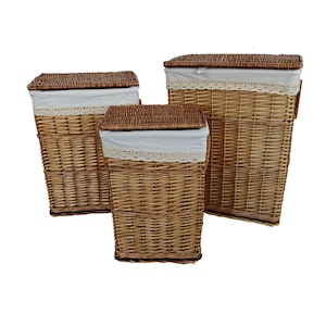 Puede incluir: Tres cestos de mimbre trenzado para la colada de diferentes tamaños. Cada cesto tiene forma rectangular, tapa marrón y forro de tela blanca con ribete de encaje. Los cestos son de color marrón natural y están diseñados para guardar la ropa sucia.
