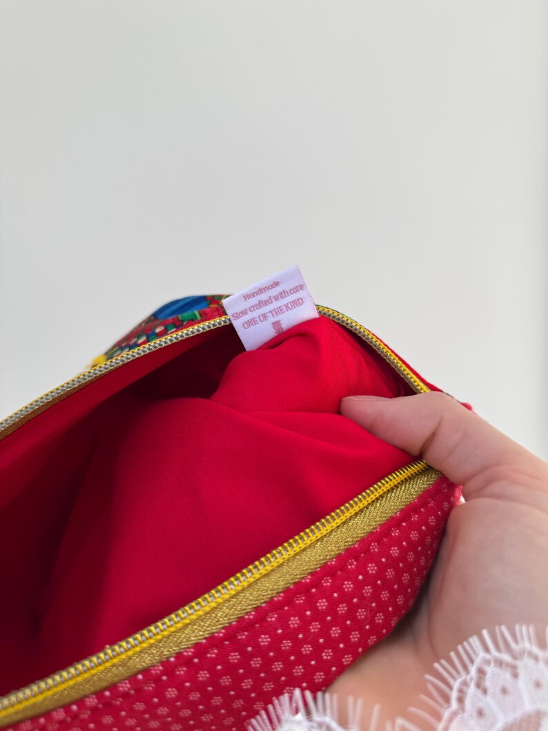 Peut inclure: Trousse de maquillage rouge avec une fermeture &eacute;clair dor&eacute;e et des pois blancs. L'int&eacute;rieur est rouge vif. Une &eacute;tiquette indique "Handmade, slow crafted with care, ONE OF THE KIND."