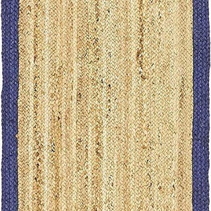 May include: Rectangular jute rug with a natural beige center and a dark blue braided border. The rug's texture is visible, showcasing the woven fibers. This rug is suitable for various home decor styles.