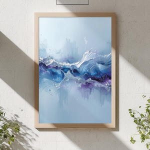 May include: Abstract art print in a light wood frame. The artwork features a blend of blue, purple, and white hues, creating a dynamic, flowing composition. The painting is displayed in a modern, well-lit living room setting.