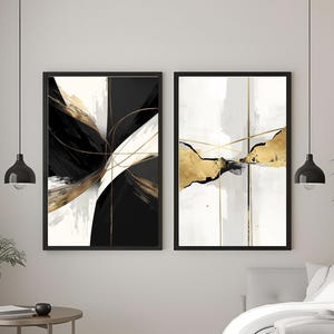 Può includere: Due opere d'arte astratte incorniciate. Una presenta pennellate nere, bianche e oro, l'altra ha forme oro e nere su sfondo bianco. Entrambe sono in cornici nere, creando un'estetica moderna. L'opera d'arte è esposta in una camera da letto.