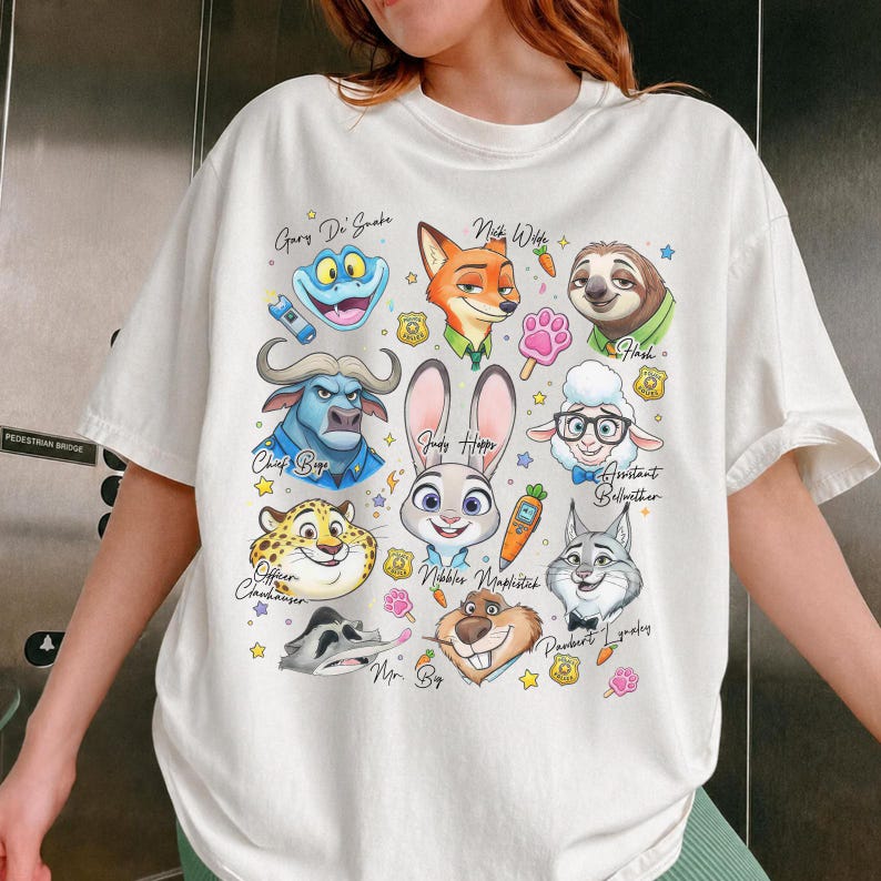 Vintage-inspired white Zootopia graphic tee for men and women. This oversized shirt captures a nostalgic 90s vibe with a detailed character print including Pawbert Lynxley and Nibbles Maplestick. A classic Disney movie merchandise piece, perfect for matching family shirts or a solo park day outfit. The crisp white fabric makes the colorful character art pop. Made from premium soft cotton for a comfortable, relaxed fit. An essential addition to any Pixar or Disney fan's wardrobe collection.