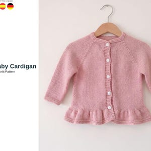 May include: A light pink baby cardigan with long sleeves and a ruffled hem, hanging on a wooden hanger. The cardigan has white buttons down the front. Text on the left says "Dadi Baby Cardigan Knit Pattern".