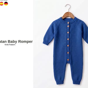 Op de afbeelding: Een blauwe gebreide babyromper met lange mouwen en houten knopen. De romper hangt aan een houten hanger tegen een witte achtergrond. De tekst "Menhatan Baby Romper Knitt Pattern" is zichtbaar.