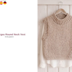 Peut inclure: Un gilet beige tricoté avec un col rond, présenté sur un cintre en bois. Le gilet a un col et un ourlet côtelés, et le texte "Vargas Round Neck Vest" est visible. Le gilet est superposé à une chemise blanche.