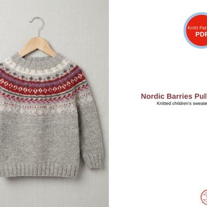 Könnte beinhalten: Ein grauer Kinderpullover mit farbenfrohem Kragendesign. Das Joch hat rote, lila und weiße Muster. Der Pullover hängt an einem Holzbügel. Der Text lautet "Nordic Barries Pullover" und "Knitted children's sweater."