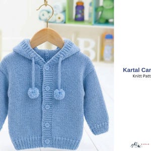 May include: A light blue knitted cardigan with a hood, hanging on a wooden hanger. The cardigan has a button-up front and two small pom-poms. The text "Kartal Cardigan Knitt Pattern" is visible on the right side.