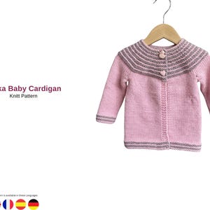 Puede incluir: Un cárdigan rosa para bebé con cuello y puños a rayas grises, colgado de una percha de madera. El cárdigan tiene dos botones en forma de corazón y el texto "Halka Baby Cardigan Knit Pattern".