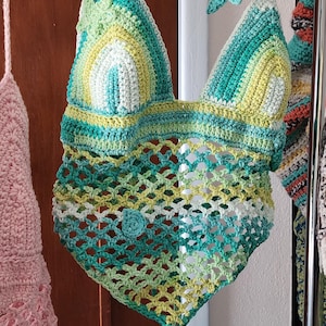 Pu&ograve; includere: Un top all'americana lavorato all'uncinetto a mano con corpetto triangolare a righe orizzontali nei toni del verde acqua, verde lime e bianco. La parte inferiore presenta un motivo a rete aperta in tonalit&agrave; verdi coordinate con orlo a punta.