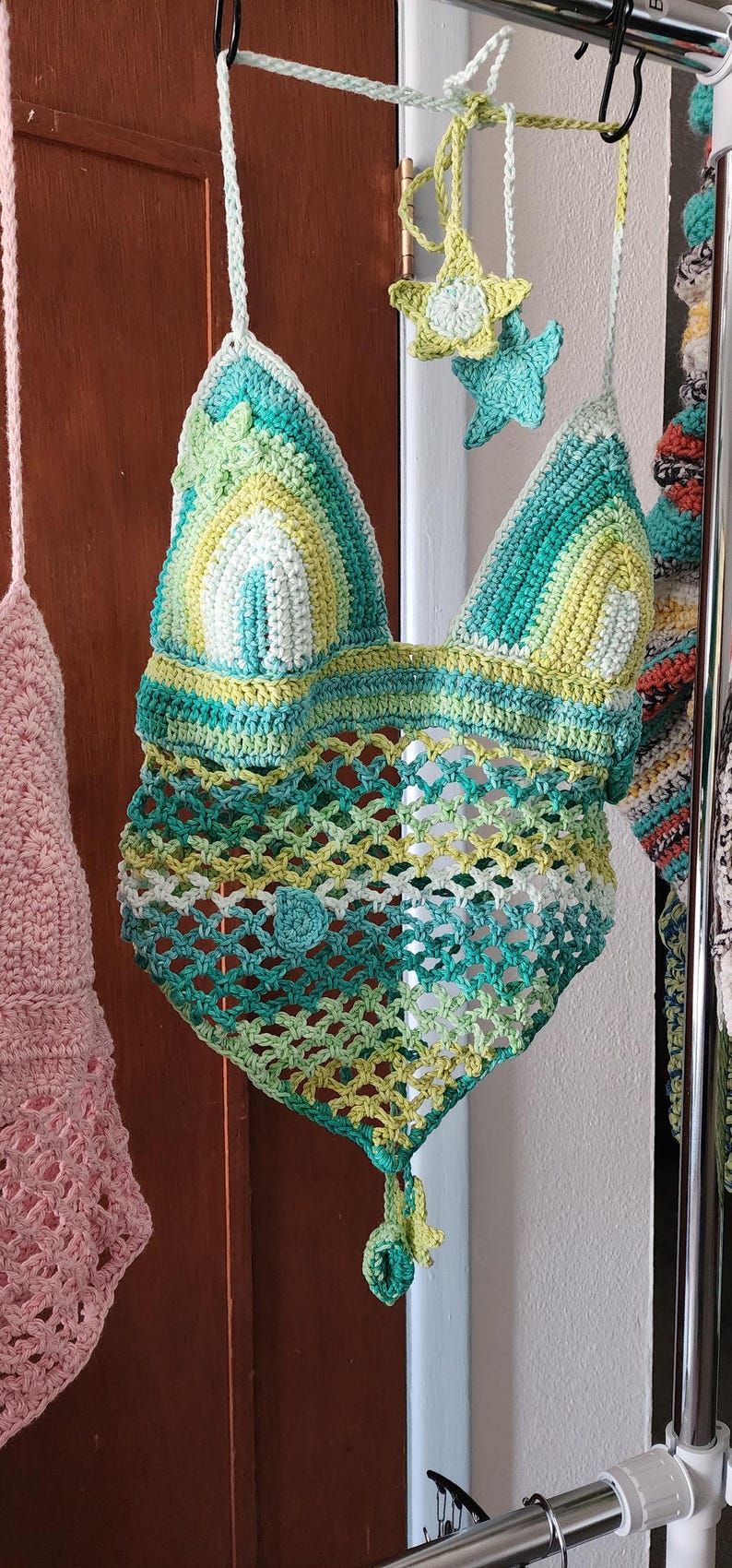 Pu&ograve; includere: Un top all'americana lavorato all'uncinetto a mano con corpetto triangolare a righe orizzontali nei toni del verde acqua, verde lime e bianco. La parte inferiore presenta un motivo a rete aperta in tonalit&agrave; verdi coordinate con orlo a punta.