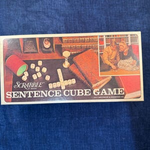 May include: Vintage Scrabble Sentence Cube Game box. The box shows a game in progress, with books, dice, and a couple playing. The game's title is displayed in white letters. A retro board game.