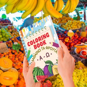 以下が含まれることがあります： 赤い文字で「COLORING BOOK」と書かれた、スパイラル綴じの塗り絵。表紙にはスイカやプラムなどの果物のイラストが描かれています。背景には、バナナ、オレンジ、その他の農産物がある活気のある果物市場が写っています。