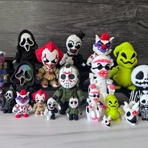 May include: A collection of various horror-themed character figurines, including figures resembling Pennywise, Jason Voorhees, Ghostface, Oogie Boogie, and Jack Skellington, displayed in multiple sizes with vibrant colors and detailed facial expressions.