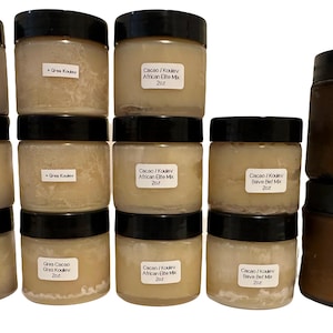 May include: A collection of jars with black lids and white labels. The jars contain a creamy, off-white substance. Labels include text such as "Cacao / Koulev African Elite Mix" and "Gres Cacao / Shea Koulev African Elite Mix".