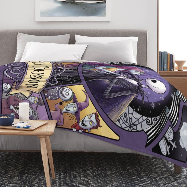 May include: A purple and black throw blanket featuring characters from The Nightmare Before Christmas. The blanket has a circular design with Jack Skellington, Sally, and other characters. The blanket is on a bed with white pillows.