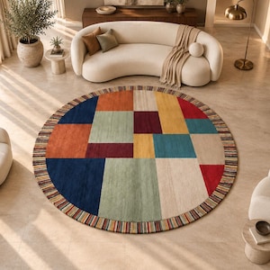 Puede incluir: Una alfombra circular grande con un patrón geométrico de bloques rectangulares en azul marino, naranja, verde salvia, burdeos, amarillo, verde azulado y crema. La alfombra tiene un borde decorativo de rayas verticales finas y multicolores.