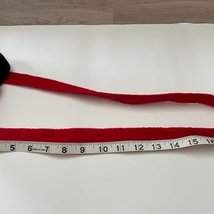 May include: A red headband with a black bow and a red bow with white polka dots. The headband measures approximately 18 inches in length. The bow is a classic design, perfect for themed parties or everyday wear.
