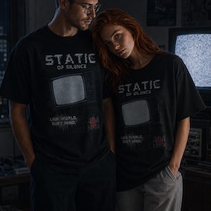 Könnte beinhalten: Schwarze T-Shirts mit dem Text "STATIC OF SILENCE" und einer Retro-Fernsehgrafik. Die Shirts zeigen auch die Sätze "LOUD WORLD, QUIET MIND" und "404 ERROR".