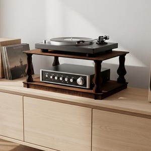 Puede incluir: Un moderno equipo de entretenimiento con un tocadiscos sobre un soporte de madera oscura, un receptor estéreo plateado y un altavoz de madera. El conjunto se coloca sobre un mueble de madera clara, creando una estética minimalista.