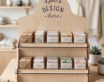 May include: A wooden display stand with two shelves, holding various soaps in boxes. The soaps are labeled with scents like "Lavender & Oat" and "Citrus Mist." The top of the stand has the text "your DESIGN .here."