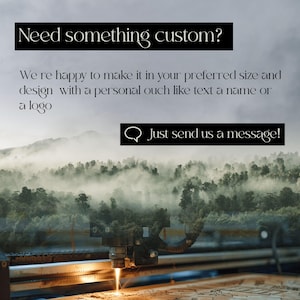 May include: Image featuring a laser cutter in operation, with text overlay: "Need something custom?" and "Just send us a message!". The background shows a misty forest scene. The text encourages custom orders.