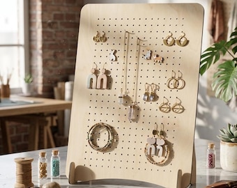 May include: A light-colored wooden jewelry display stand with numerous earrings, necklaces, and bracelets. The stand has a pegboard design with small holes for hanging jewelry. The jewelry includes gold and silver tones, with various shapes and designs.