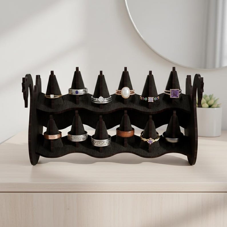 May include: A dark brown wooden ring display stand with multiple ring holders. The stand is holding various rings with different designs and gemstones. The stand is on a light-colored surface.