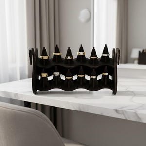May include: A dark brown wooden ring display stand with two tiers, holding various rings. The rings are gold and silver, with some featuring gemstones. The stand is on a white marble surface.