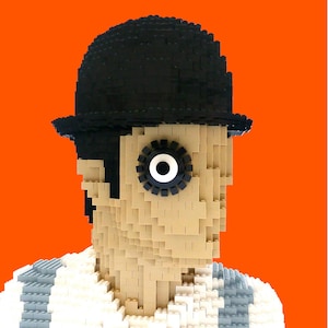 May include: A Lego sculpture of a character wearing a black bowler hat and a white shirt with gray stripes. The character has one large eye with a white center and black outline. The background is a solid orange.