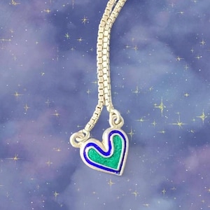 May include: A silver-toned box chain necklace featuring a heart-shaped pendant. The pendant has a metallic silver border, a vibrant green center, and a thin blue enamel outline. The chain is flexible and consists of small, square-shaped links.