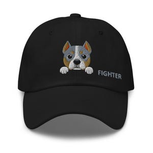 Könnte beinhalten: Schwarze Baseballkappe mit einem gestickten Hundegesicht. Der Hund hat graues, weißes und braunes Fell. Das Wort "FIGHTER" ist in Grau auf die Seite gestickt. Ein lässiges Accessoire für Hundeliebhaber.