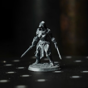 May include: A white ceramic mug with a black handle and the text "But First, Coffee" in a bold, black font. The mug is set against a blurred background, suggesting a cozy setting.