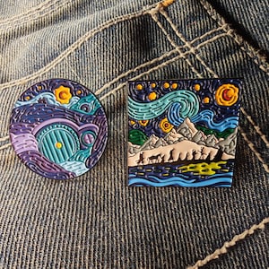 Può includere: Due spille smaltate. Una spilla rotonda presenta un design a porta di hobbit nei toni del viola, del verde acqua e del giallo. L'altra spilla quadrata raffigura una scena notturna stellata con montagne e figure, in blu, giallo e bianco.