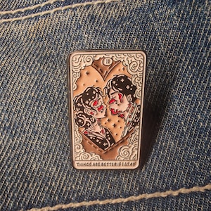 Puede incluir: Un pin rectangular de esmalte con una pareja besándose dentro de un marco en forma de corazón. El pin tiene un borde marrón con nubes y estrellas blancas. El texto "THINGS ARE BETTER IF I STAY" está en la parte inferior.