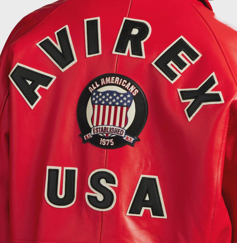 May include: Red leather jacket with the word "AVIREX" across the top and "USA" at the bottom in black letters with white trim. A circular patch in the center reads "ALL AMERICANS ESTABLISHED 1975" with a design of the American flag.