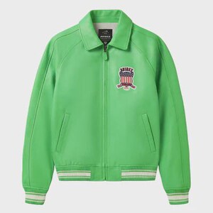 K&ouml;nnte beinhalten: Leuchtend gr&uuml;ne Lederjacke mit Kragen und Rei&szlig;verschluss. Sie hat einen Brustaufn&auml;her mit patriotischem Design und wei&szlig;-gr&uuml;n gestreifte B&uuml;ndchen und Saum. Die Jacke hat zwei Vordertaschen.