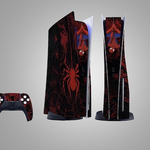 Könnte beinhalten: Ein PlayStation 5 Konsolen- und Controller-Set im Spider-Man-Design. Konsole und Controller haben ein rot-schwarzes Design mit Spinnennetz-Muster und einem großen Spinnen-Emblem. Das Set wird vor einem grauen Hintergrund präsentiert.
