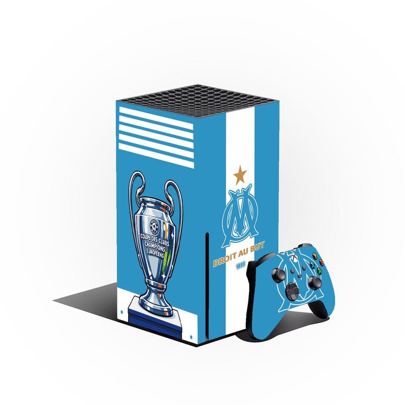 Może przedstawiać: Jasnoniebieska i biała sk&oacute;rka do konsoli do gier i kontroler z logo Olympique de Marseille, trofeum Ligi Mistrz&oacute;w i napisem "DROIT AU BUT".