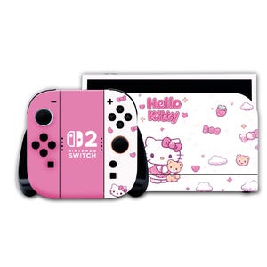May include: A pink Nintendo Switch console with a Hello Kitty theme. The console features a pink Joy-Con controller and a white screen with Hello Kitty graphics. The text "Hello Kitty" is visible on the screen.