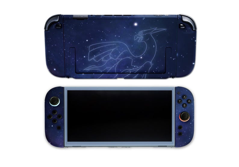 K&ouml;nnte beinhalten: Eine marineblaue Nintendo Switch-Konsole und -Dockingstation mit einem Sternennacht-Design und einer wei&szlig;en Umrisszeichnung eines Fabelwesens. Die Konsole hat einen schwarzen Bildschirm und blaue Akzente auf den Controllern.