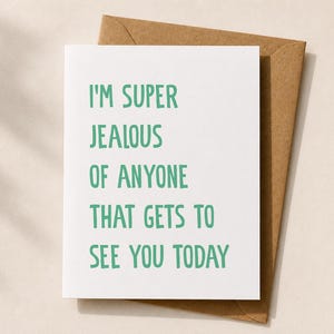Peut inclure: Une carte de v&oelig;ux blanche avec le texte "I'M SUPER JEALOUS OF ANYONE THAT GETS TO SEE YOU TODAY" en lettres vertes, plac&eacute;e sur une enveloppe marron. La carte et l'enveloppe sont pos&eacute;es sur un fond neutre.