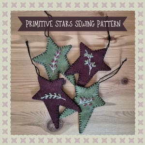 May include: Four handmade star ornaments in shades of green and burgundy, each with embroidered floral details. The stars are connected with black string and are displayed on a wooden surface. The banner reads "Primitive Stars Sewing Pattern".