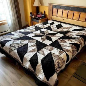 May include: A starburst patterned quilt in black, white, and patterned fabric, displayed on a bed with a wooden headboard. The quilt's design incorporates geometric shapes and detailed stitching. The quilt is a handmade item.