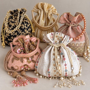 May include: Five drawstring pouches featuring intricate embroidery, beadwork, and sequins. The collection includes a black bag with gold floral patterns, a gold bag with vertical stripes, a pink bag with floral motifs, a peach bag with lace, and a white bag with mirrors.